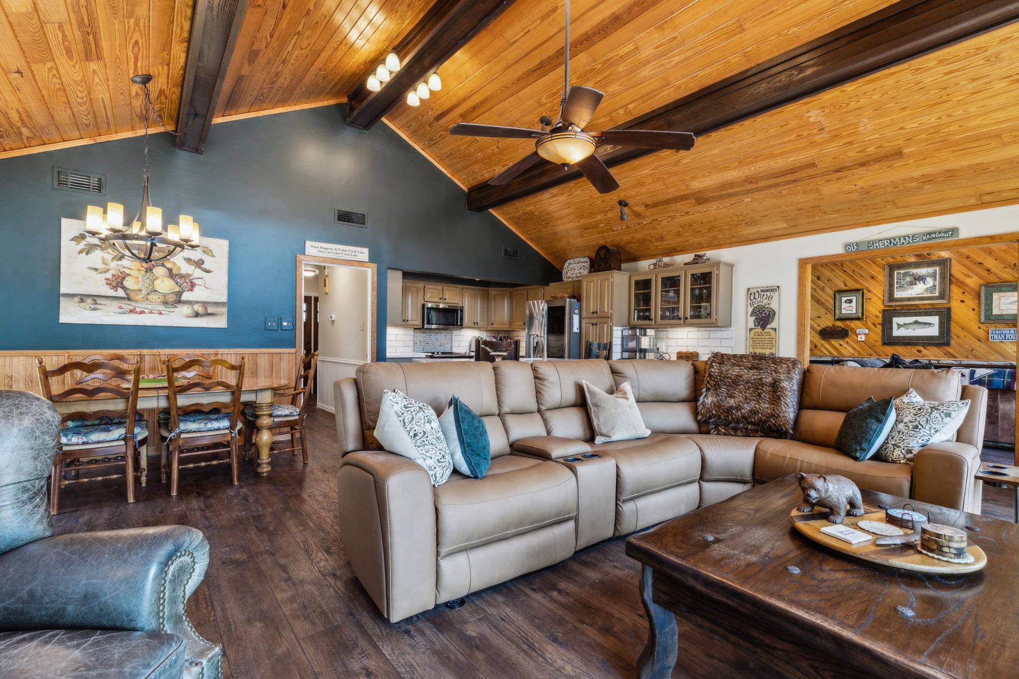 Open-concept living room with vaulted cedar ceilings, stone fireplace, and lake views